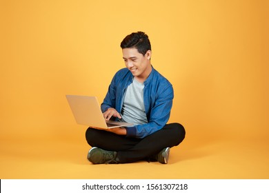 Asian Man Use Of The Laptop Computer Against Color Orange Background