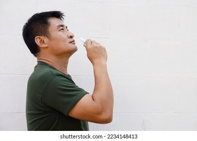 Asian man uses inhaler to smell  for relieve dizzy and faint symptoms. Concept , health problem, sickness and remedy. Increases freshness, reduces dizziness and stuffy nose. self take care.           