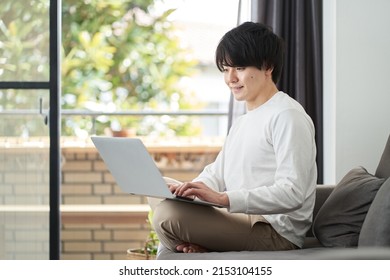 Asian man using a computer in his living room
