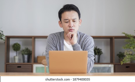 Asian Man Using A Computer In The Living Room