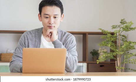 Asian man using a computer in the living room - Shutterstock ID 1879990723
