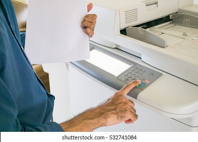 Asian Man Using Copy Machine. Finger Pressing The Start Button On A Multifunction Printer Or Copier.