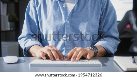 Asian man using desktop computer in home office, close up hand typing keyboard. People working at home or internet information technology concept