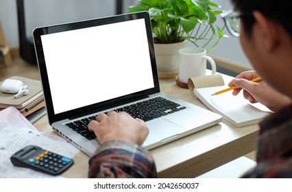 Asian Man Using Laptop Computer And Calculator For Calculating Bills At Home.