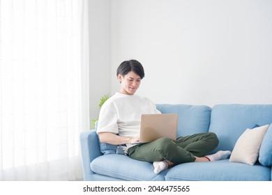 Asian Man Using The Laptop On The Sofa