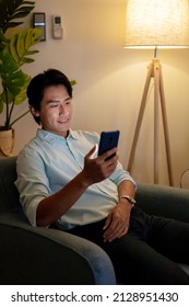 asian man is using mobile phone at night in living room