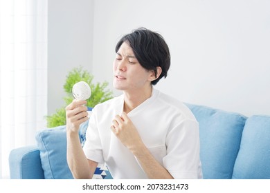 Asian Man Using The Portable Fan At Home