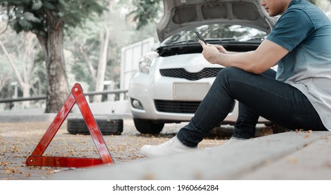 Asian Man Using Smartphone For Assistance After A Car Breakdown On Street. Concept Of Vehicle Engine Problem Or Accident And Emergency Help From Professional Mechanic