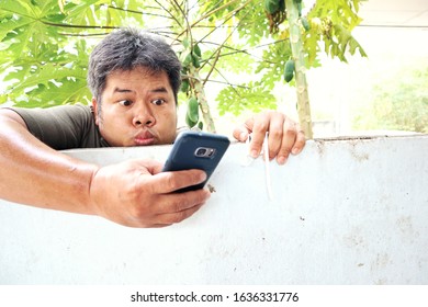 Asian man using a smartphone on cement wall, Copy space 