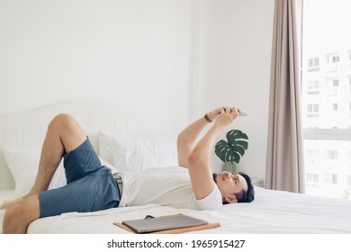 Asian Man Is Using The Smartphone On His Bed In Concept Of Relaxation.