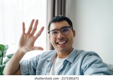 Asian man using smartphone for online video conference call with friends waving hand making hello gesture - Powered by Shutterstock