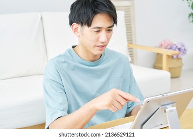 Asian Man Using The Tablet At Home