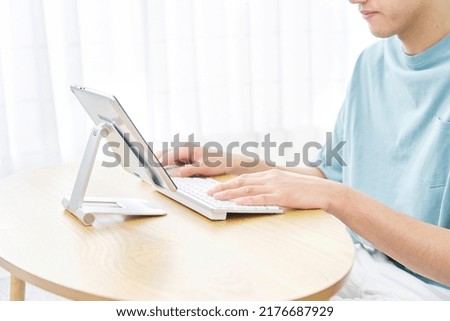 Asian man using the tablet at home, no face