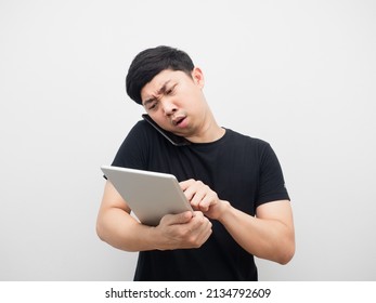 Asian Man Using Tablet With Talking Mobile Phone Busy And Serious Emotion