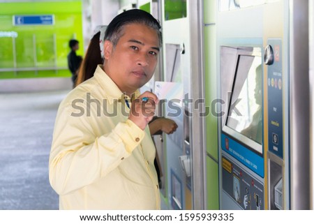 Asian man using vending ticket machines to take the skytrain in Thailand