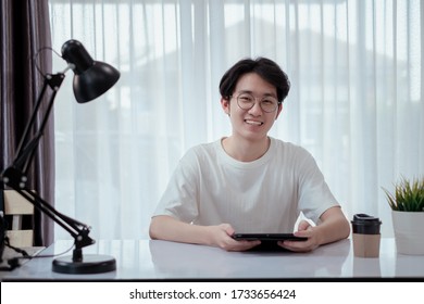 Asian Man Video Conference User Interface With Tablet Online Remotely Working From Home Social Distancing Discuss Business With Internet Video Call Technology When Quarantine, Stay Home.