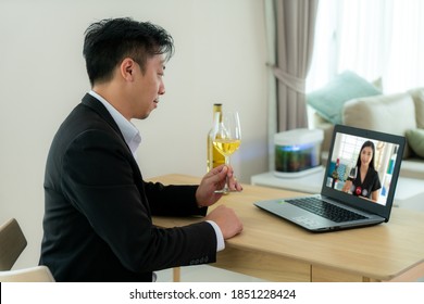 Asian Man Virtual Happy Hour Meeting Party And Drinking White Grape Wine Online Together With His Friend In Video Conference With Digital Tablet For A Online Meeting In Video Call
