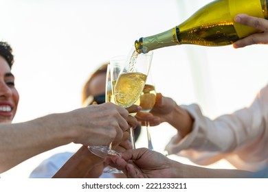 Asian man waiter pouring and serving champagne to passenger tourist while catamaran yacht boat sailing in the sea at summer sunset. Man and woman enjoy luxury outdoor lifestyle on travel vacation.