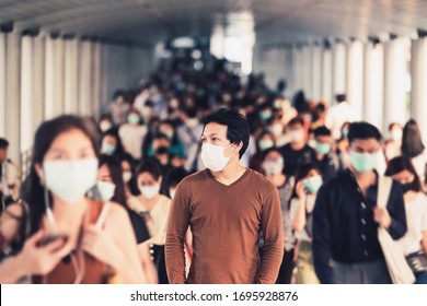 Asian Man Walking And Standing Between Crowd Of Blurred Unrecognizable Business People Wearing Surgical Mask For Prevent Coronavirus Outbreak In Rush Hour Working Day At Bangkok Transportation