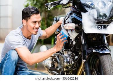 Asian Man Washing His Motorcycle Or Scooter With Soap And Sponge