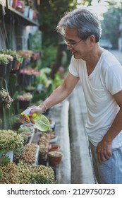 Asian Man Watering Home Plant At Home Garden