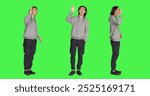 Asian man waving hello at people, greeting someone with a smile and confidence against full body greenscreen template. Young adult saying hi with a wave, smiling and feeling positive in studio.