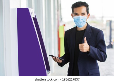 Asian Man Wear Mask Protect Coronavirus Covid19 And Then Man Uses A Mobile Phone To Dial The Cash Withdrawal Code At An ATM. Business Finance Technology