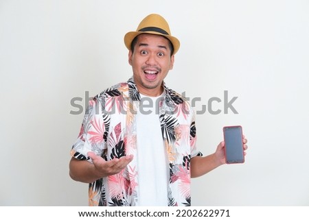 Asian man wearing beach shirt showing empty handphone screen with excited expression