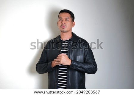 Asian man wearing black leather jacket showing fierce face expression