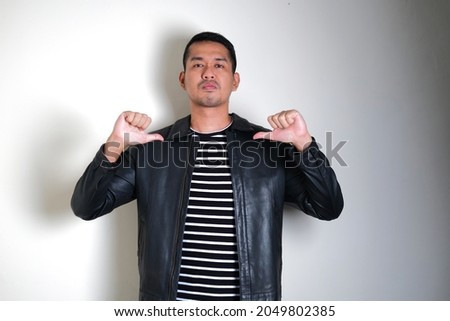 Asian man wearing black leather jacket pointing his self with arrogant expression