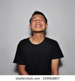 Asian Man Wearing Black Tshirt With Happy Expression On Grey Background