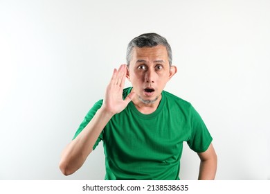 Asian Man Wearing Casual Green Tshirt Isolated On White Background Looks Surprised.

