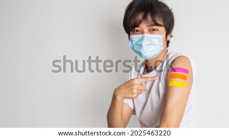 Asian man wearing face mask with a smile on his face showing his vaccinated arm. fight against virus covid-19 coronavirus, Vaccination and immunization. vaccine booster concept.