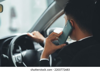 Asian Man Wearing Formal Suit In The Car, He Is Talking On The Phone While Driving Is Reckless And Illegal Driving, Traveling By Car, Safe Driving, Respecting Traffic Rules.