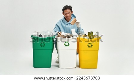 Asian man wearing gloves sorting garbage in glass, plastic and cardboard dustbins. Ecology safety and protection. Waste disposal and recycling. Isolated on white background. Studio shoot. Copy space