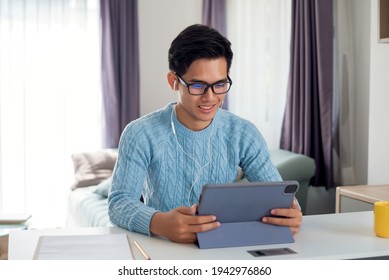 Asian Man Wearing Headphones Are Happy To Work At Home And Using A Tablet.