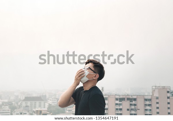 Asian man wearing hygiene mask and sick because of\
air pollution in the\
city.