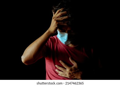 Asian man wearing a mask has a headache and has difficulty breathing after contracting Covid-19 even after undergoing treatment.