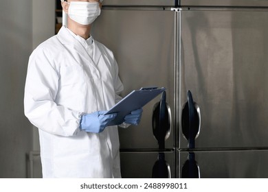 Asian man wearing sanitary clothes inspecting the kitchen - Powered by Shutterstock