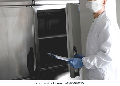 Asian man wearing sanitary clothes inspecting the kitchen - Powered by Shutterstock