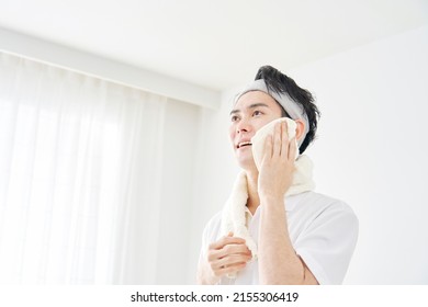 Asian Man Wiping His Face With A Towel