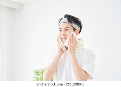 Asian Man Wiping His Face With A Towel