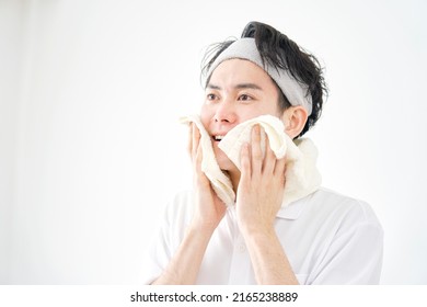 Asian Man Wiping His Face With A Towel