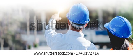 Asian man and woman engineer with the blue safety helmet meeting at the construction site.-panoramic banner