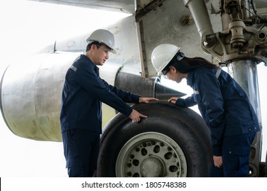 Asian Man And Woman Engineer Maintenance Airplane Team Repairs, Fixes, Modernization And Renovation In Front Airplane From  In Airport.
