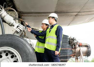 Asian Man And Woman Engineer Maintenance Airplane Team Repairs, Fixes, Modernization And Renovation In Front Airplane From  In Airport.
