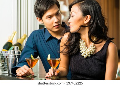 Asian Man And Woman In Flirting Intimately At Bar Drinking Cocktails