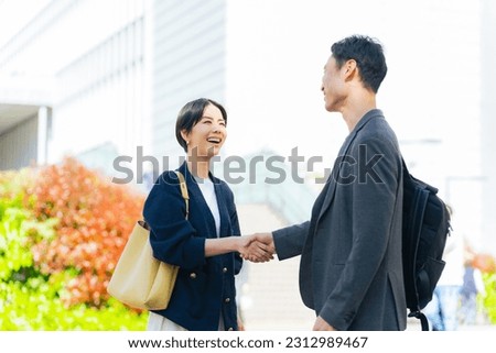 Asian man and woman shaking hands in front of modern city. business greeting.