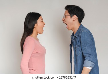 Asian Man And Woman Shouting At Each Other Over Grey Background, Couple Fighting