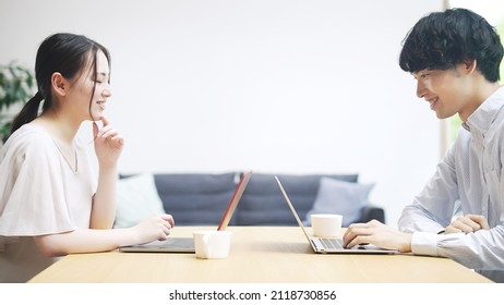 Asian Man And Woman Using A Laptop PC In The Room.